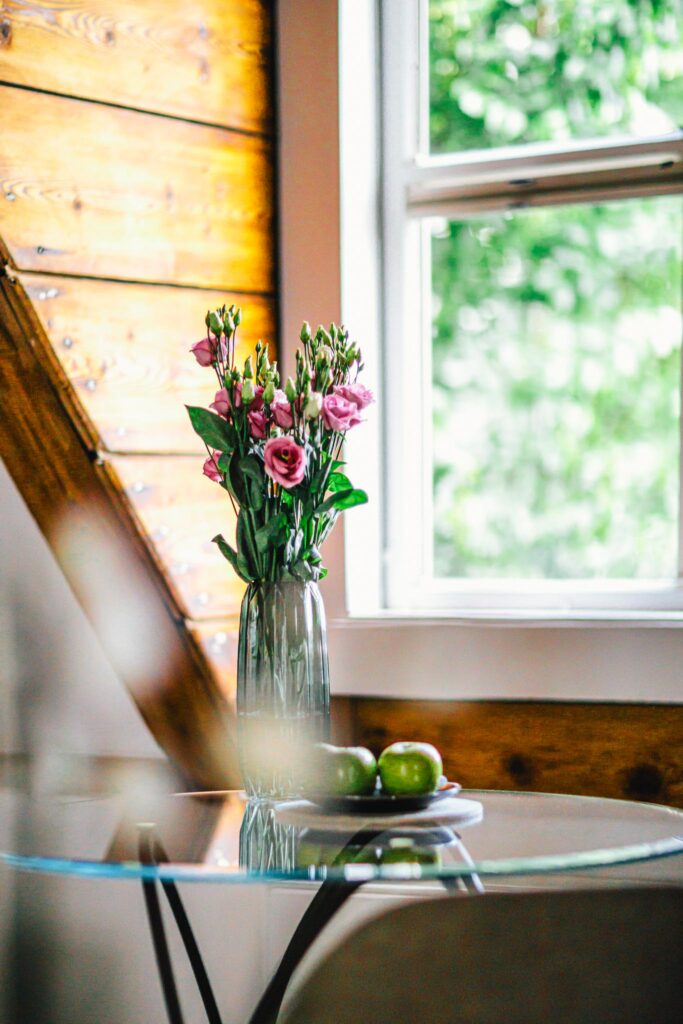 A table with a vase with pink rose flowers and three green apples on it, in a room at luxury boutique hotel Royal Gate Resort, member of The Leading Hotels of The World.