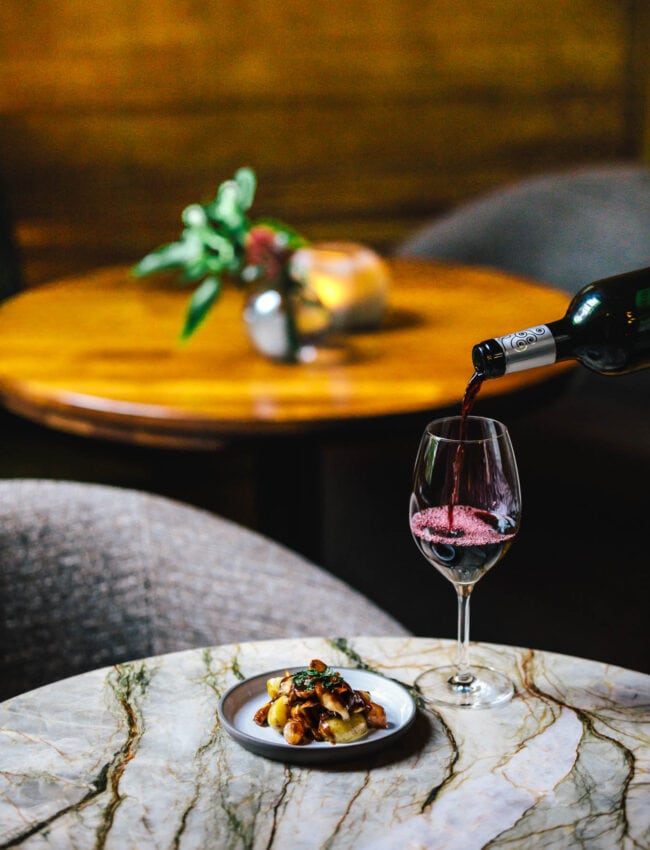 Pouring a glass of wine with a small dish during a High Wine at Bar Brasserie OCCO at Royal Gate Resort, part of The Leading Hotels of The World.