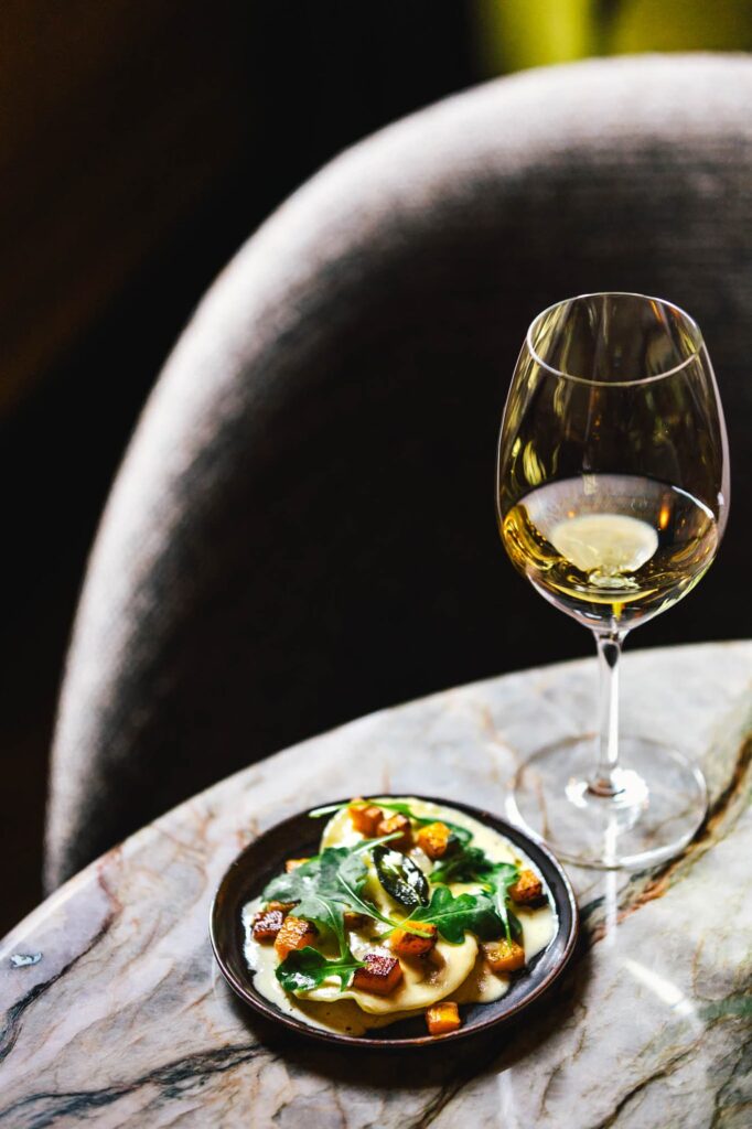 High Wine tasting setup at Royal Gate Resort, a luxury Leading Hotels of the World property, with a chilled white wine and gourmet dish.