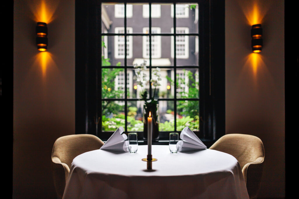 Table at two michelin star Restaurant Vinkeles at luxury boutique hotel Royal Gate Resort overlooking the secluded garden terrace in the Jordaan area in Amsterdam. Part of the Leading Hotels of The World.