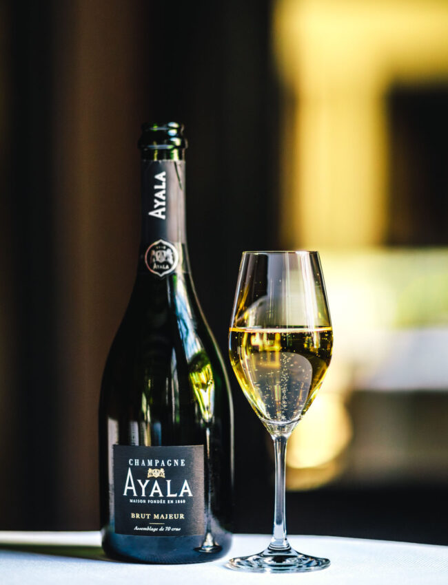 Glass of Ayala Brut Majeur Champagne and a flute glass of bubbly in Vinkeles, a restaurant which gastronomy has been awarded 2 michelin stars at luxury boutique hotel Royal Gate Resort, part of the Leading hotels of The World (LHW)