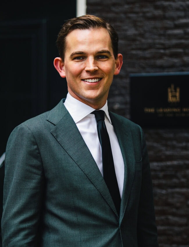 Portrait of Sam Hilkens, hotel manager, standing in front of the main door of hotel Royal Gate Resort, a boutique hotel member of The Leading Hotels of The World